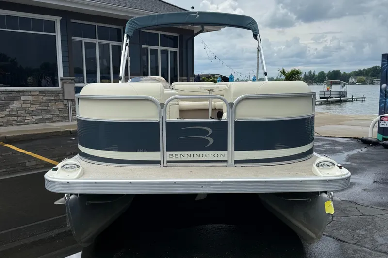 Slide: The Image of 2009 Bennington 1850GL pontoon boat docked near a lakeside building. - 2