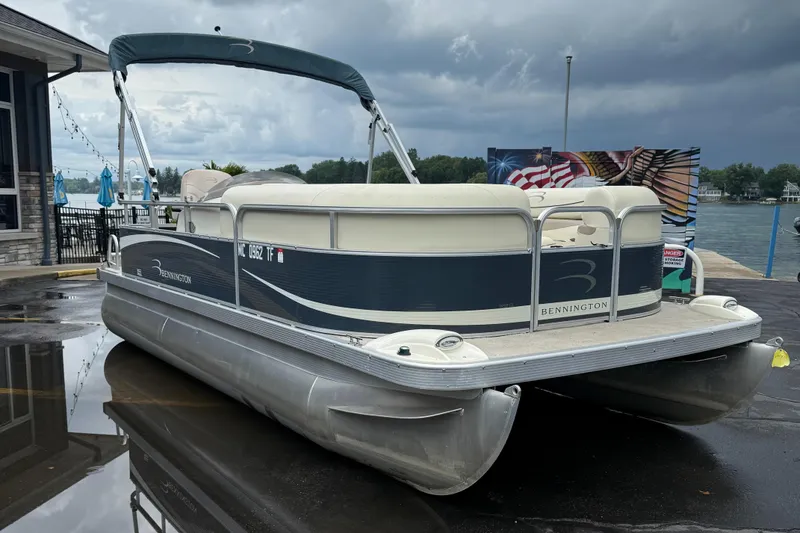 Slide: The Image of 2009 Bennington 1850GL pontoon boat docked by a lakeside under cloudy skies. - 3