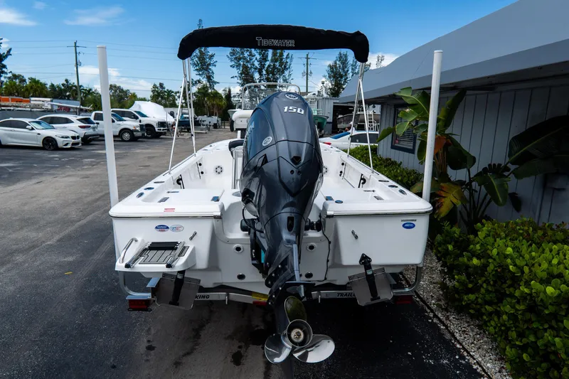 Slide: The Image of 2026 Tidewater 2110 Bay Max boat with outboard motor, parked outdoors. - 3