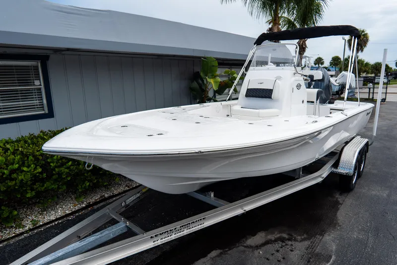 Slide: The Image of 2026 Tidewater 2110 Bay Max boat on trailer, parked near a building with palm trees. - 4