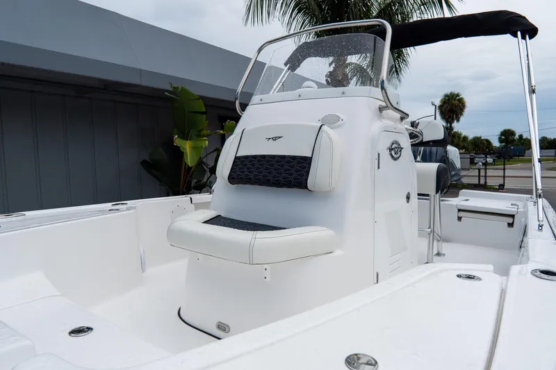 Slide: The Image of 2026 Tidewater 2110 Bay Max boat interior with seating and console, under a cloudy sky. - 6