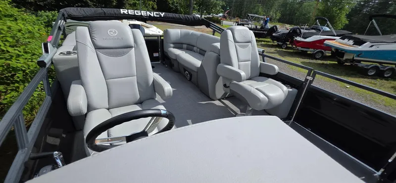Slide: The Image of 2022 Regency 230 LE3 pontoon boat interior with plush seating and steering wheel. - 11
