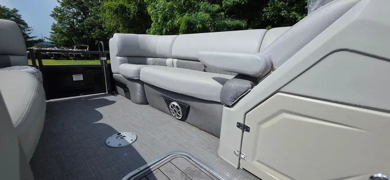 Slide: The Image of 2022 Regency 230 LE3 boat interior with gray seating and lush green background. - 16