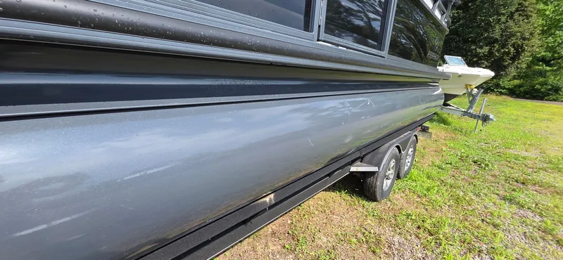 Slide: The Image of 2022 Regency 230 LE3 boat on trailer, side view, parked on grass. - 17