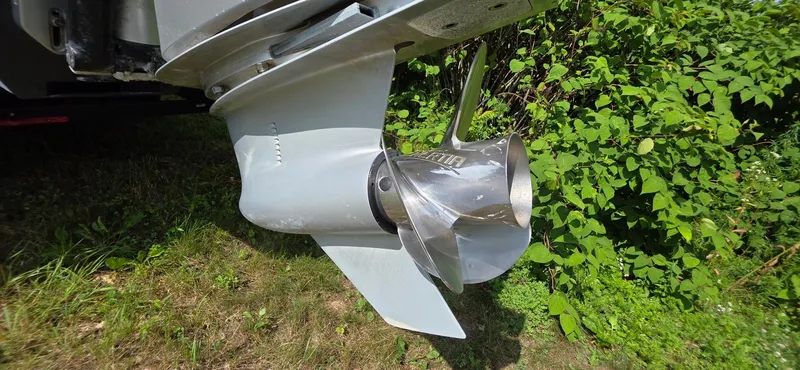 Slide: The Image of 2022 Regency 230 LE3 boat propeller in grassy area, showcasing sleek design and metallic finish. - 19