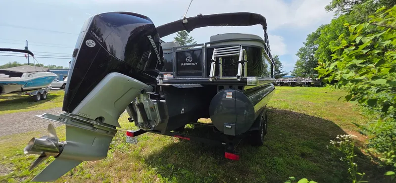 Slide: The Image of 2022 Regency 230 LE3 pontoon boat with Mercury outboard motor, parked on grass. - 20