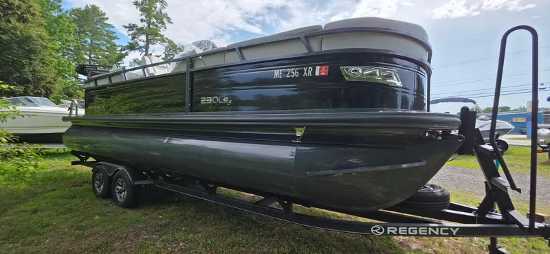 Slide: The Image of 2022 Regency 230 LE3 pontoon boat on trailer, parked outdoors. - 21