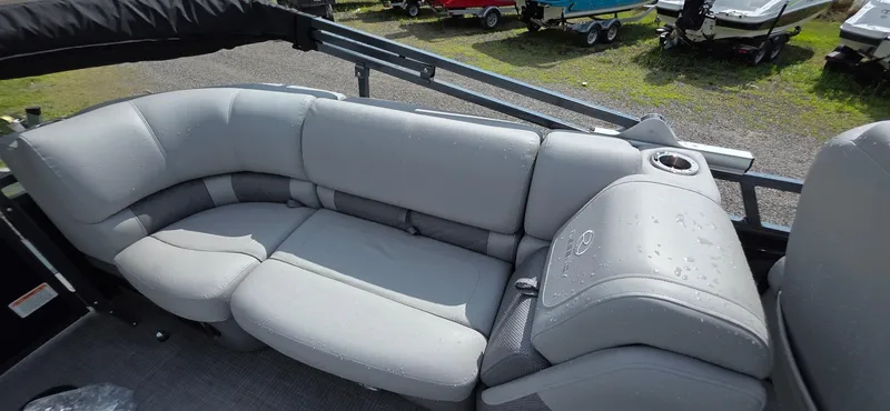 Slide: The Image of 2022 Regency 230 LE3 boat interior with gray seating and cup holder, outdoors. - 8