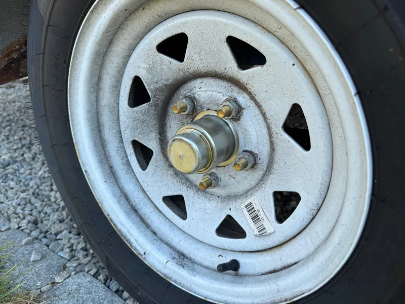Slide: The Image of Close-up of a 2001 Hurricane FunDeck GS 201 OB trailer wheel on gravel. - 25