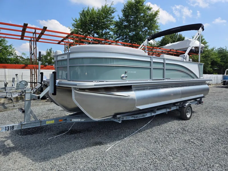 The Image of 2026 Harris Cruiser 210 pontoon boat on a trailer, parked outdoors. - 0