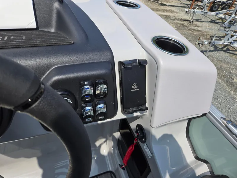 Slide: The Image of 2026 Harris Cruiser 210 dashboard with controls, cup holders, and phone mount. - 19