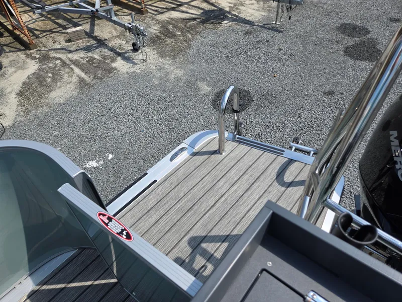 Slide: The Image of 2026 Harris Cruiser 210 boat deck with ladder and railing, parked on gravel. - 28