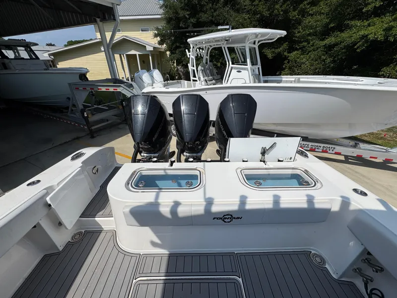 Slide: The Image of 2022 Fountain 38TE boat with triple outboard engines, docked near a yellow house. - 40