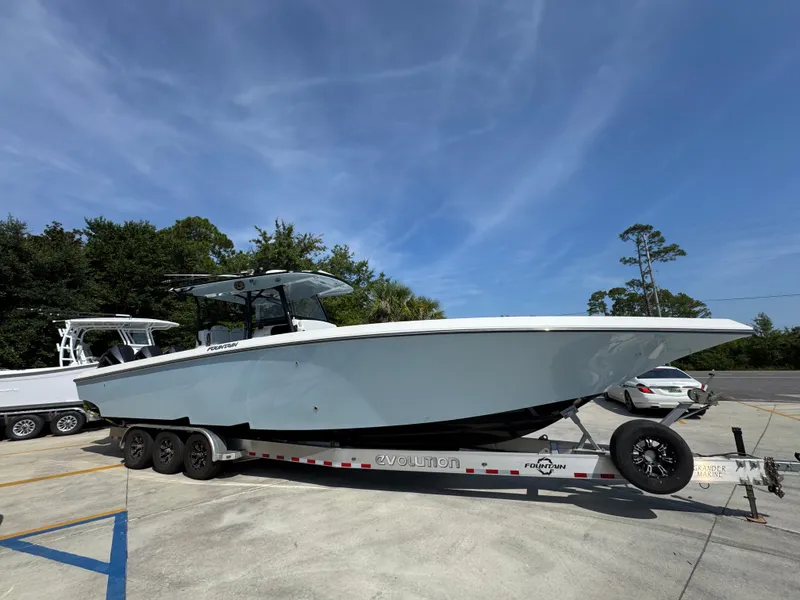 Slide: The Image of 2022 Fountain 38TE boat on trailer, parked outdoors under clear blue sky. - 9
