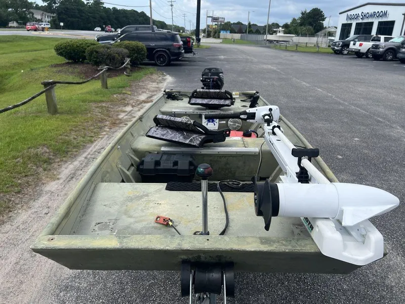 Slide: The Image of 2010 Triton 14' Jon boat with motor, parked outdoors near showroom. - 6