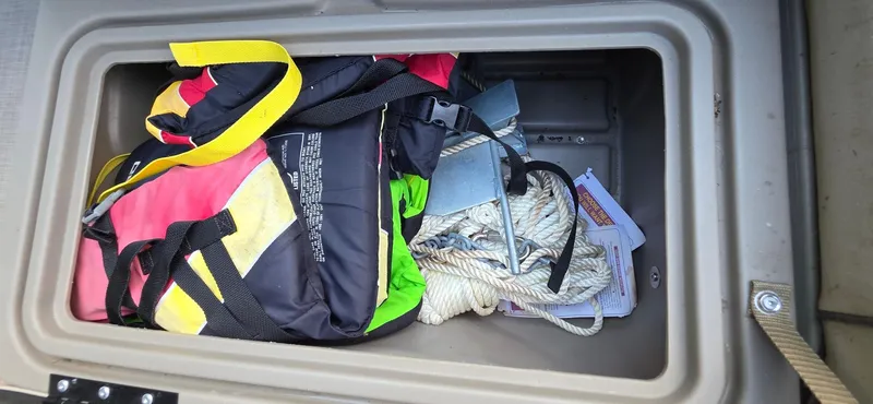 Slide: The Image of Storage compartment of 2021 Sun Tracker 22 Party Barge RF with life jackets and anchor. - 16