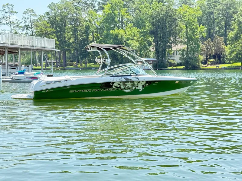 Slide: The Image of 2008 Nautique Super Air 230 boat on a serene lake with lush greenery. - 5