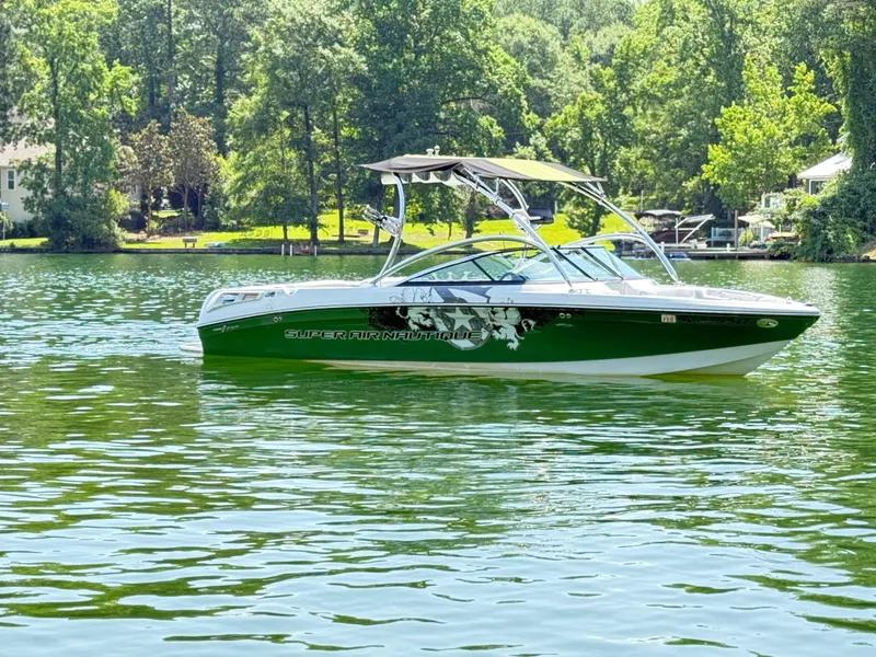Slide: The Image of 2008 Nautique Super Air 230 boat on a serene lake with lush greenery. - 6