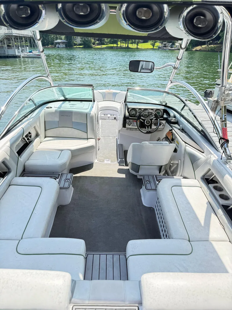 Slide: The Image of 2008 Nautique Super Air 230 boat interior with spacious seating and modern dashboard on a lake. - 8