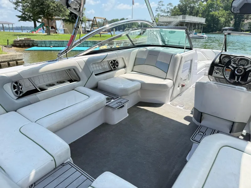 Slide: The Image of 2008 Nautique Super Air 230 boat interior with white seating and steering wheel, docked by a lake. - 9