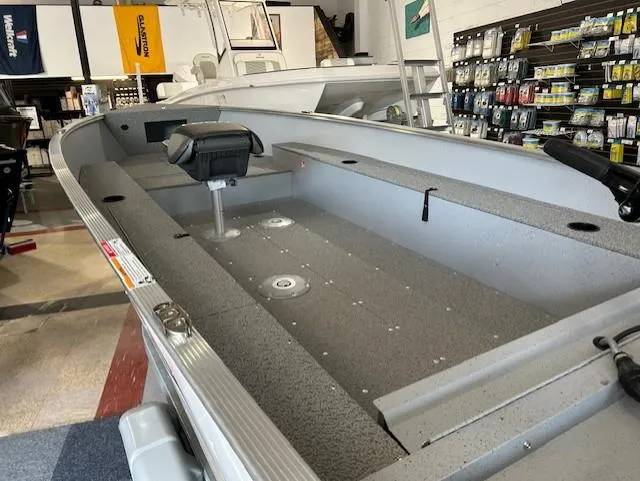 Slide: The Image of 2026 Lund 1600 Fury Tiller boat interior in showroom, featuring seating and storage compartments. - 4