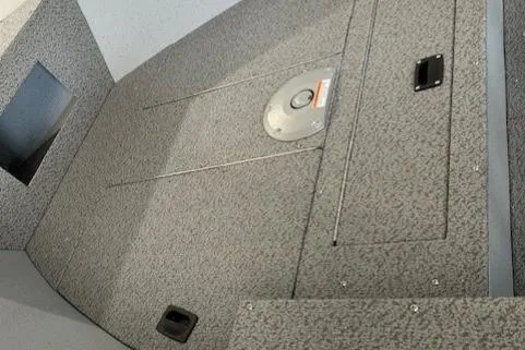 Slide: The Image of 2026 Lund 1600 Fury Tiller boat interior with storage compartments and textured flooring. - 5