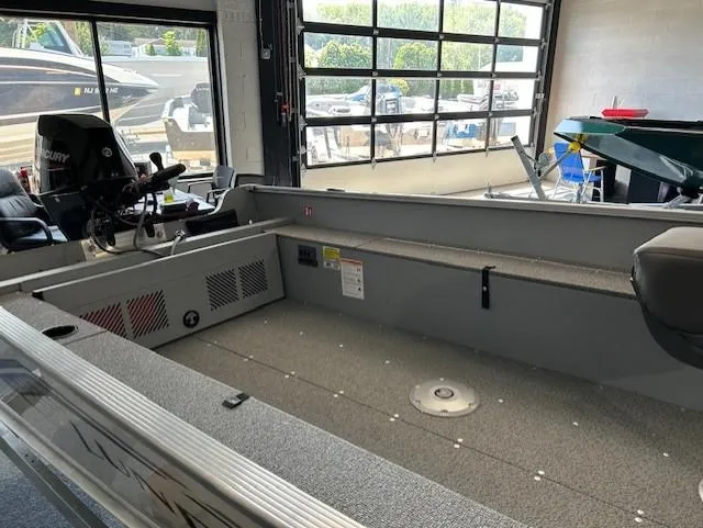 Slide: The Image of 2026 Lund 1600 Fury Tiller boat interior in showroom, featuring spacious deck and modern controls. - 8