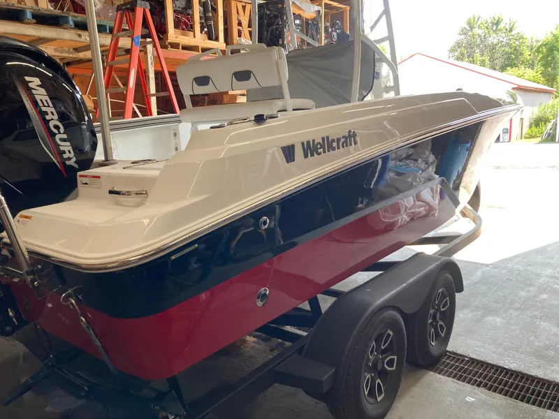 Slide: The Image of 2022 Wellcraft 202 Fisherman boat on trailer, featuring a Mercury engine, in a storage area. - 37