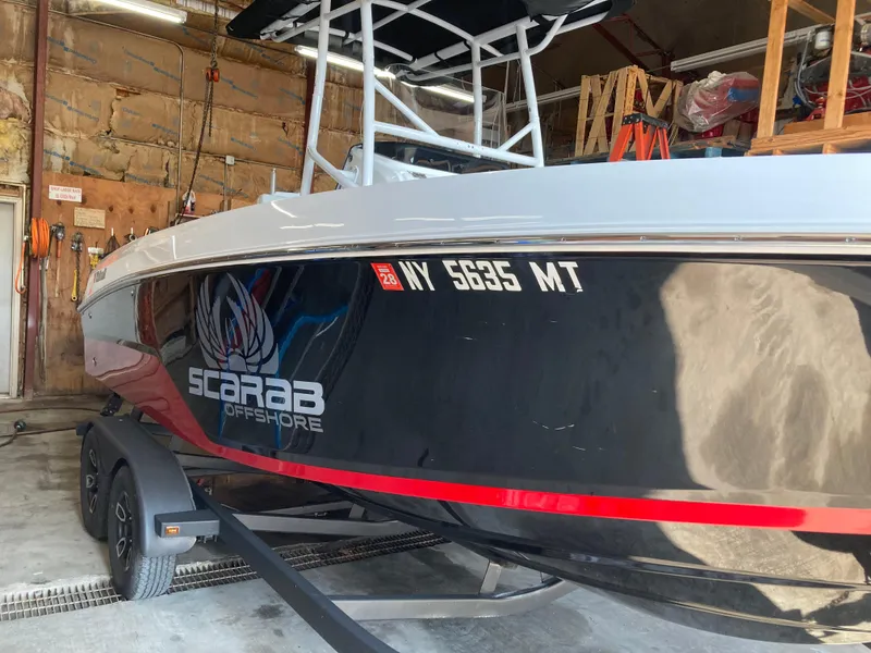 Slide: The Image of 2022 Wellcraft 202 Fisherman boat in garage, black hull with "Scarab Offshore" logo. - 39