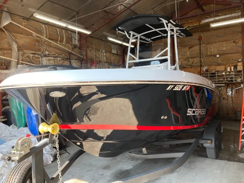 Slide: The Image of 2022 Wellcraft 202 Fisherman boat in a garage, black hull with red accents. - 40