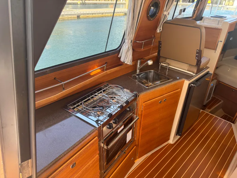 Slide: The Image of 2019 Ranger Tugs R-29 CB boat interior with seating and wood flooring at a marina. - 4