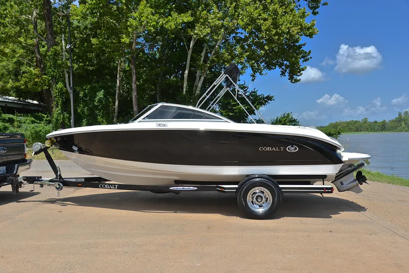 Slide: The Image of 2011 Cobalt 200 boat on trailer by a lake, surrounded by trees and blue sky. - 11