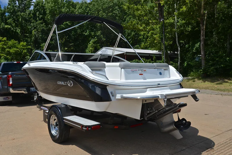 Slide: The Image of 2011 Cobalt 200 boat on trailer, parked outdoors with trees in background. - 12