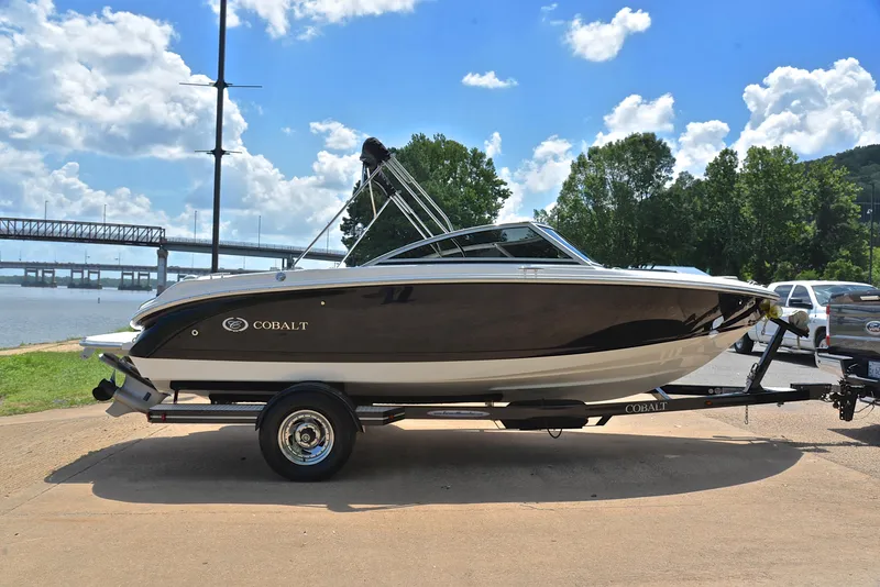 Slide: The Image of 2011 Cobalt 200 boat on trailer by river, under blue sky with clouds. - 15