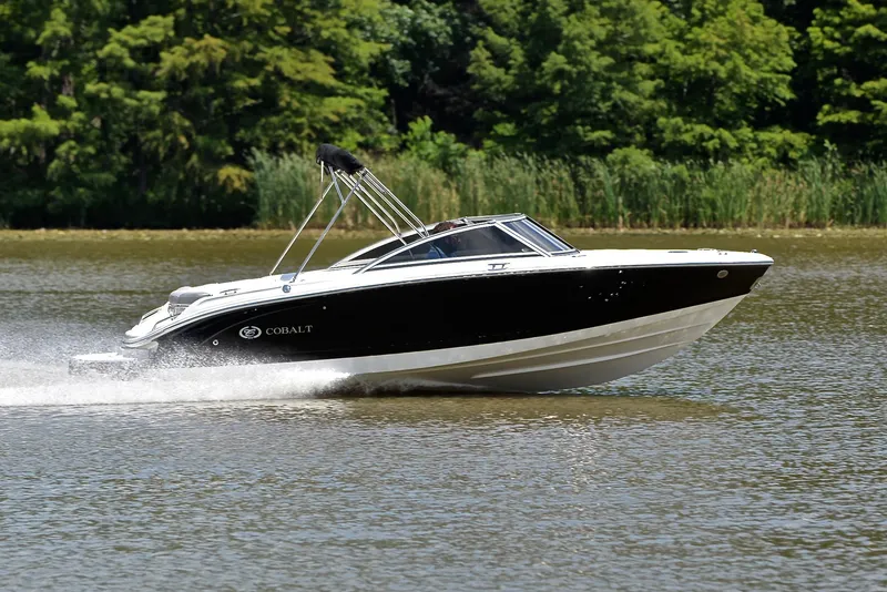 Slide: The Image of 2011 Cobalt 200 boat cruising on a lake with lush green trees in the background. - 3