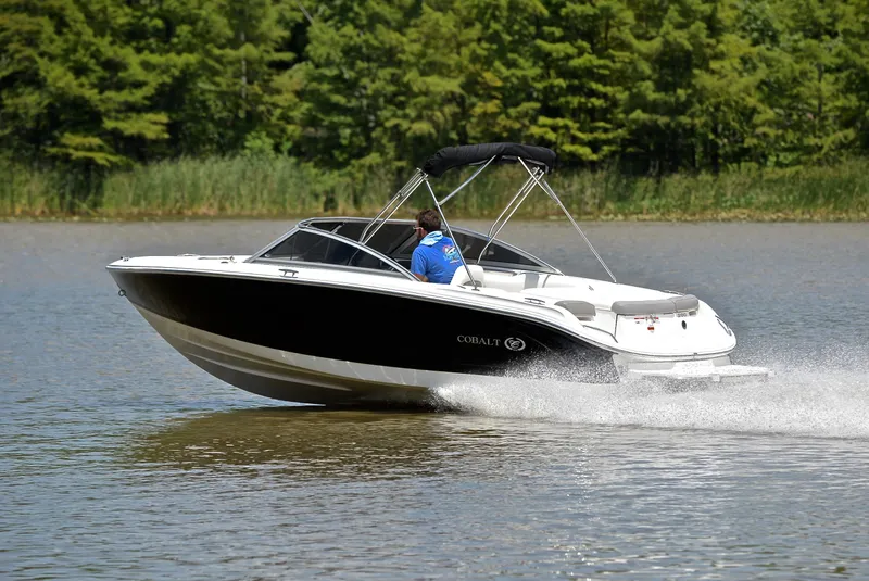 Slide: The Image of 2011 Cobalt 200 boat cruising on a lake with lush green trees in the background. - 4