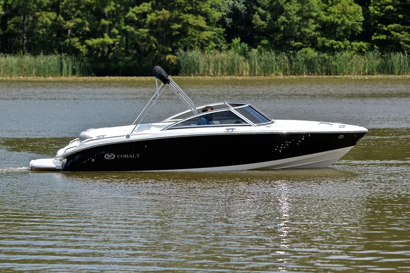 Slide: The Image of 2011 Cobalt 200 boat cruising on a calm lake with lush greenery in the background. - 7