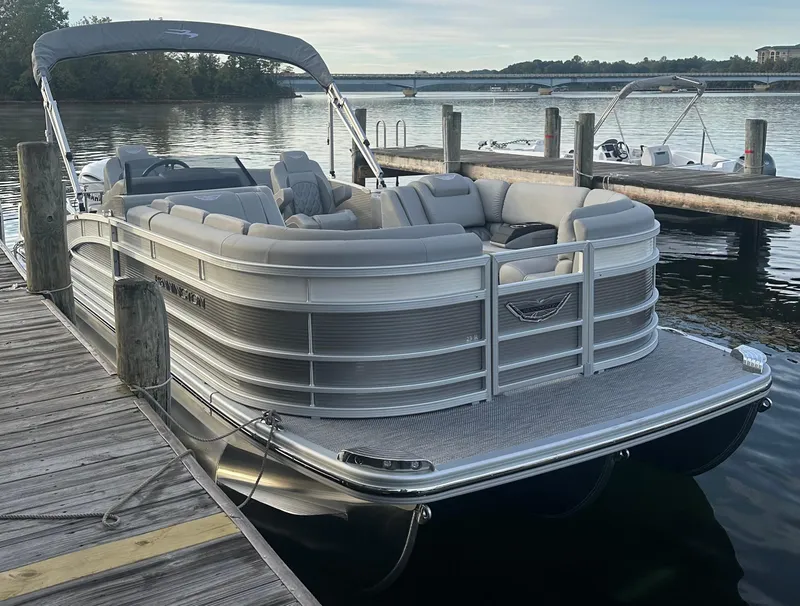 Slide: The Image of 2024 Bennington R 23 Swingback pontoon boat docked on a serene lake. - 1