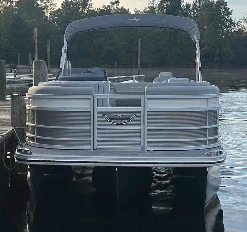 Slide: The Image of 2024 Bennington R 23 Swingback pontoon boat docked on calm water. - 2