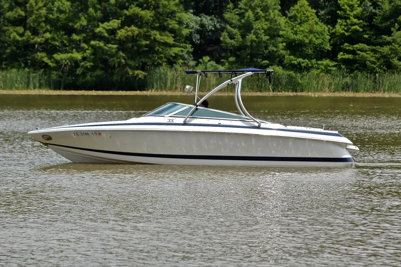 Slide: The Image of 2000 Cobalt 246 boat on a calm lake with lush green trees. - 10