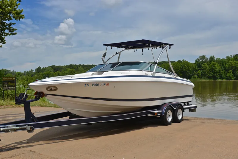Slide: The Image of 2000 Cobalt 246 boat on trailer by a lake, under a clear sky. - 11
