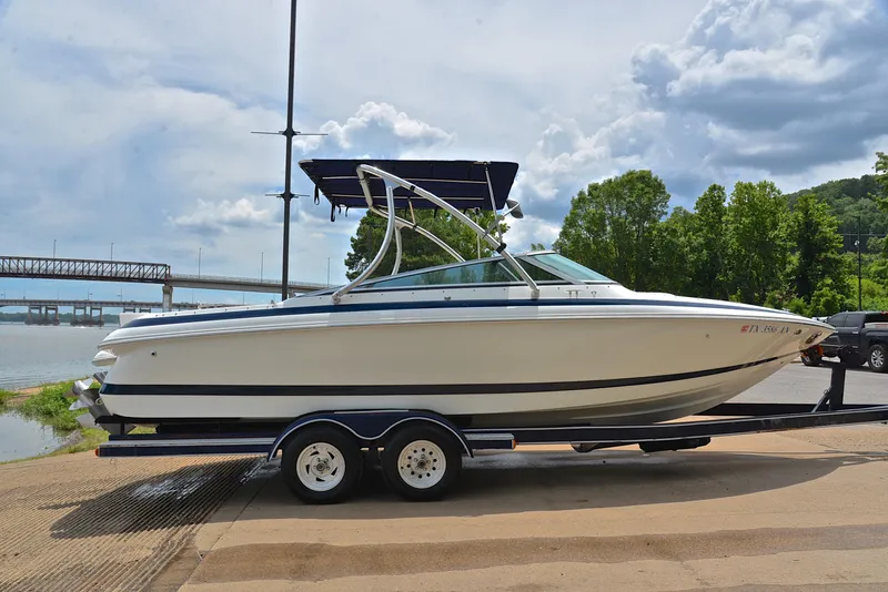 Slide: The Image of 2000 Cobalt 246 boat on trailer by riverside, under cloudy sky. - 16