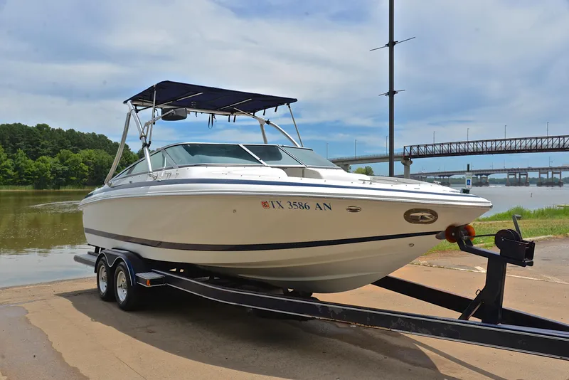 Slide: The Image of 2000 Cobalt 246 boat on trailer by river, under blue sky. - 17