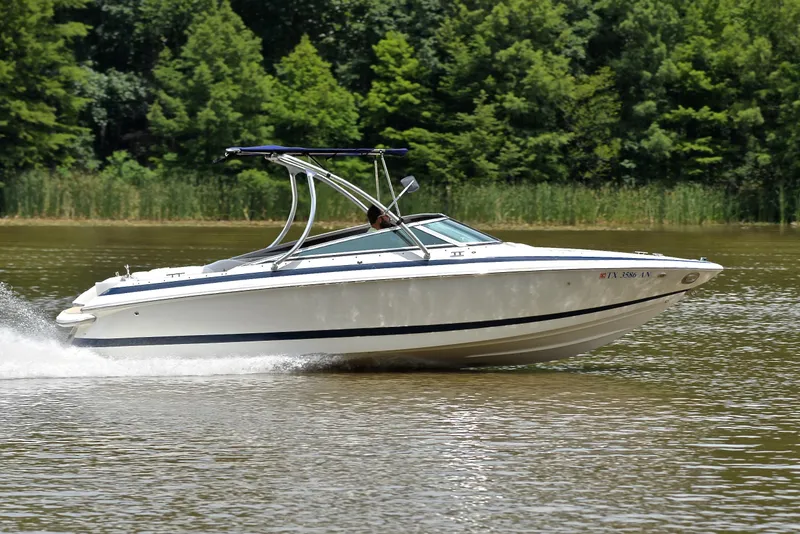 Slide: The Image of 2000 Cobalt 246 boat cruising on a lake with lush green trees in the background. - 3