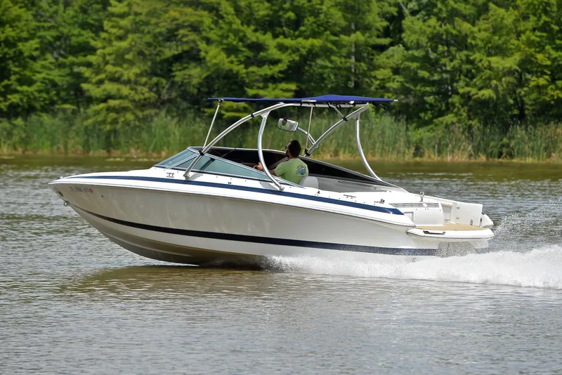 Slide: The Image of 2000 Cobalt 246 boat cruising on a lake with lush green trees in the background. - 4