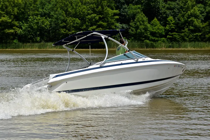 Slide: The Image of 2000 Cobalt 246 boat cruising on a lake with lush green trees in the background. - 5