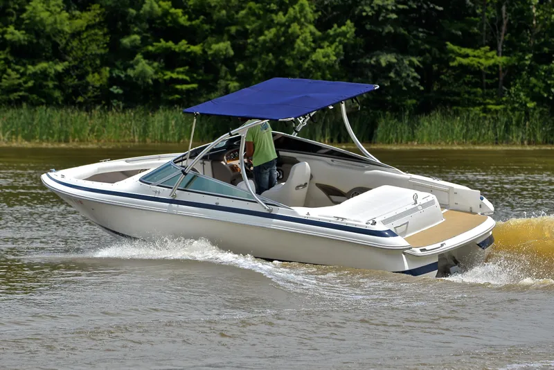 Slide: The Image of 2000 Cobalt 246 boat cruising on a lake with a blue canopy. - 7