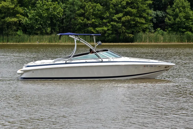 Slide: The Image of 2000 Cobalt 246 boat on a calm lake with lush green trees in the background. - 8