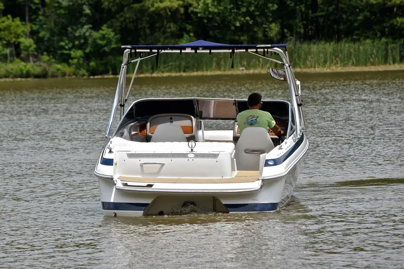Slide: The Image of A 2000 Cobalt 246 boat cruising on a calm lake with lush greenery. - 9