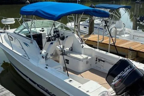 Slide: The Image of 1995 Wellcraft 23 Excel boat with blue canopy and Mercury outboard motor docked at marina. - 2